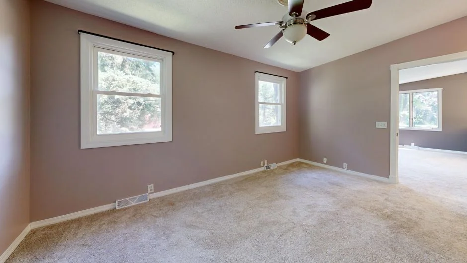 A professional cleaner in protective gear vacuuming the floor in a modern living room.